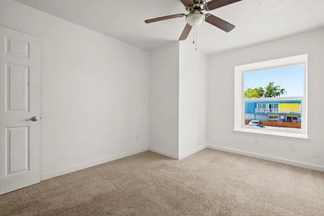 an empty room with a window and a ceiling fan