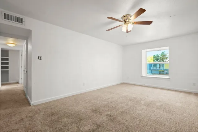 an empty room with windows and fan