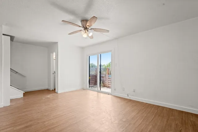 an empty room with wooden floor fan and windows