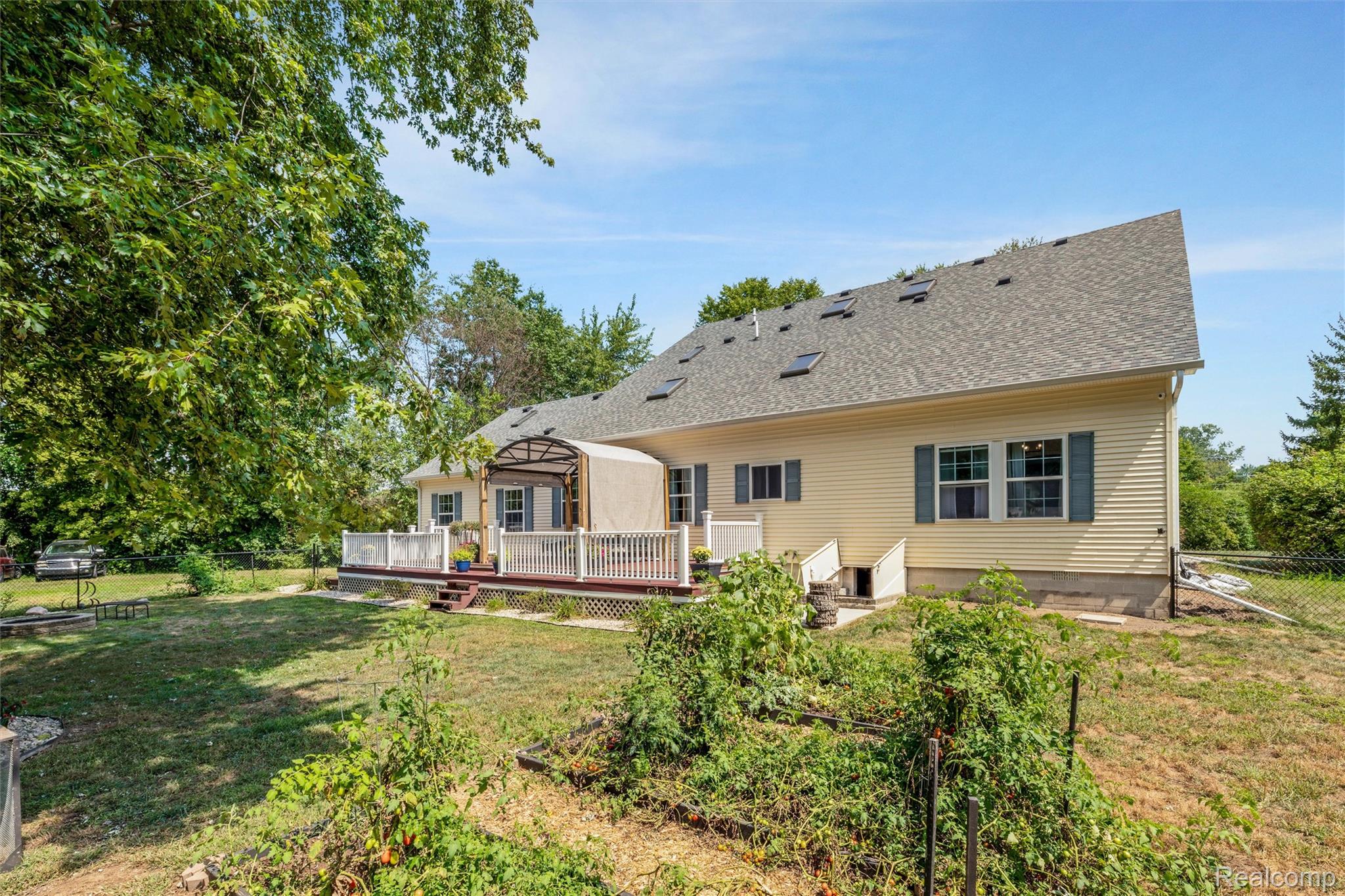 21280 Merriman Road New Boston, MI 48164 - Photo 59 of 65 Expansive exterior featuring light yellow siding, multiple skylights, a multi-level deck with white railing, and a covered patio area