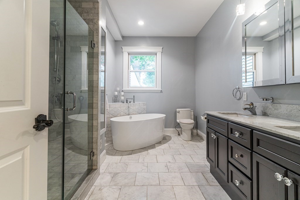 91 University Road, Unit 1 Brookline, MA 02445 - Photo 18 of 39 a spacious bathroom with a double vanity sink a toilet and a mirror