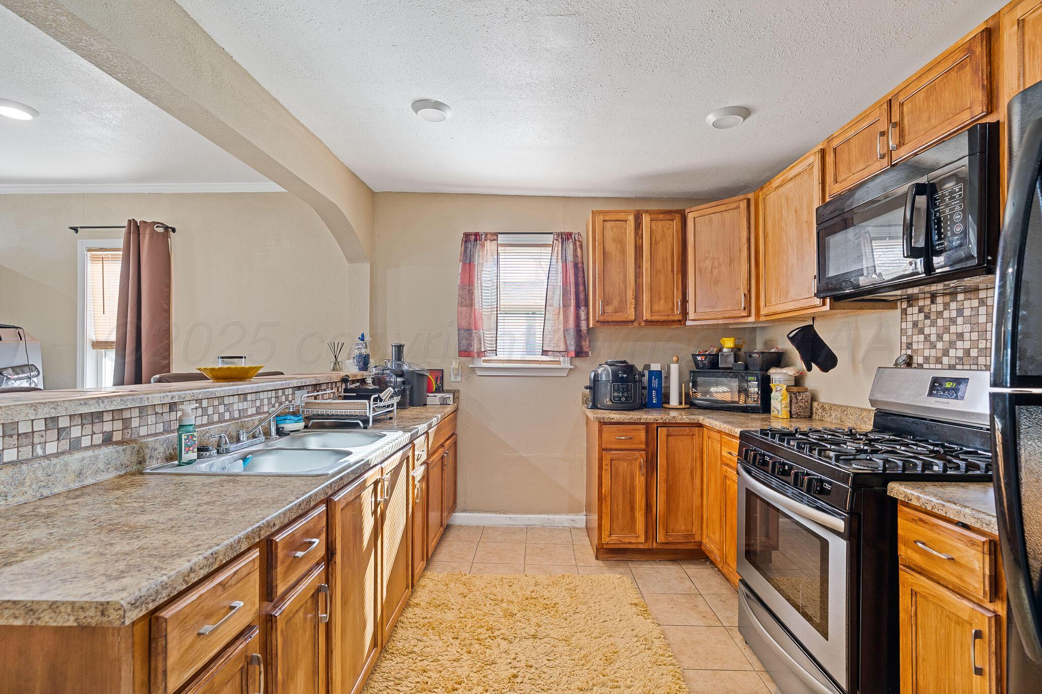 702 South Cleveland Street Amarillo, TX 79102 - Photo 6 of 11 a kitchen with stainless steel appliances granite countertop a stove a sink dishwasher and a refrigerator