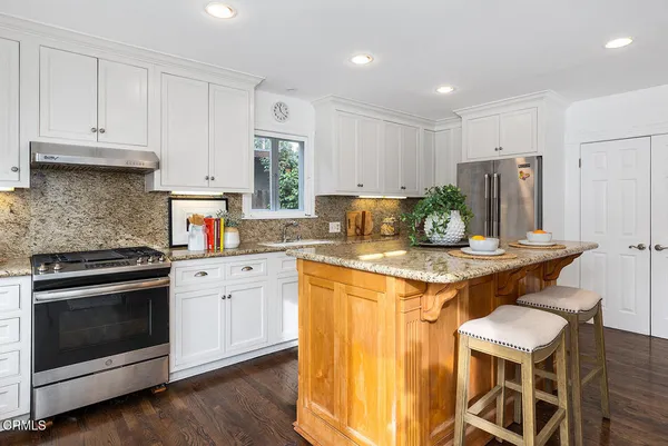 a kitchen with granite countertop a sink stainless steel appliances and window