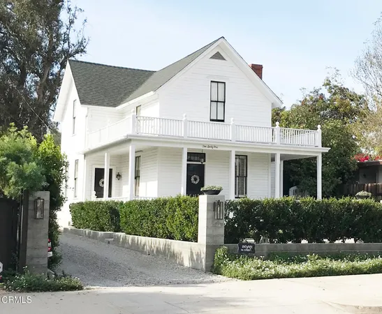 a view of white house with a yard and potted plants