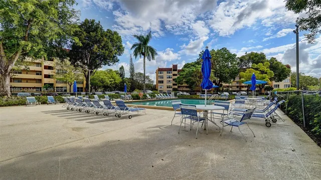 a view of a swimming pool with a table and chairs under an umbrella