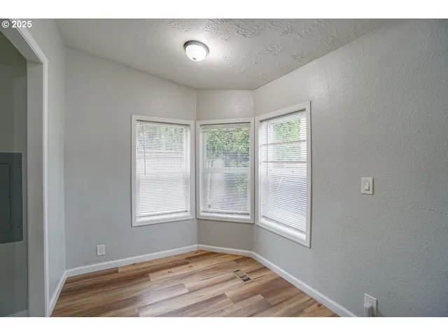 a view of an empty room with wooden floor and fan