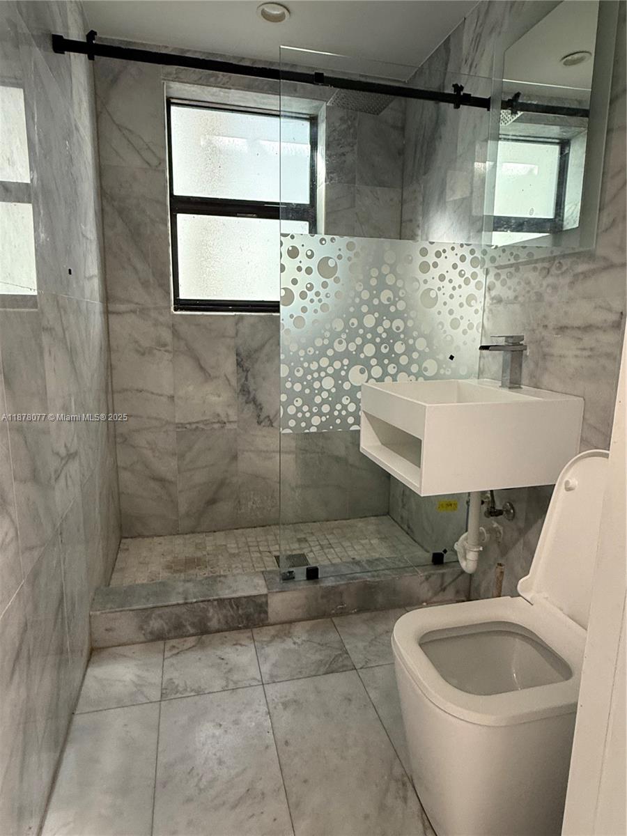 1560 Drexel Avenue, Unit 207 Miami Beach, FL 33139 - Photo 9 of 12 a bathroom with a sink a toilet and mirror