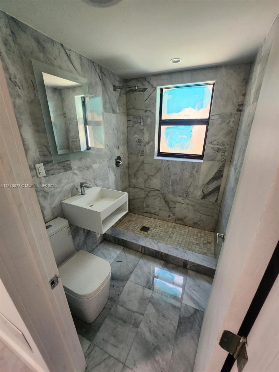 1560 Drexel Avenue, Unit 207 Miami Beach, FL 33139 - Photo 10 of 12 a bathroom with a toilet sink and mirror