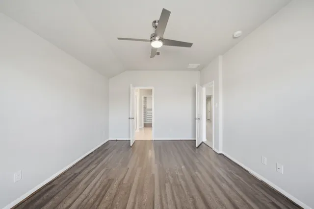 an empty room with wooden floor ceiling fan and windows