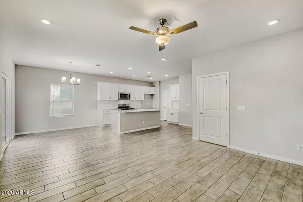 a view of an empty room with kitchen and window