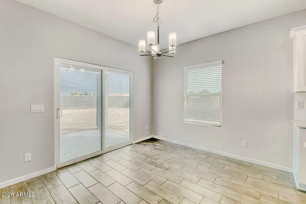 an empty room with chandelier fan and windows