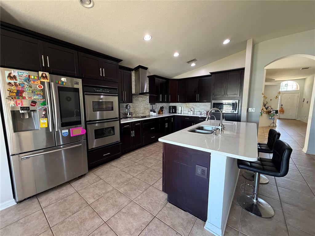 945 Tramells Trail Kissimmee, FL 34744 - Photo 14 of 36 a kitchen with stainless steel appliances kitchen island granite countertop a sink refrigerator and cabinets