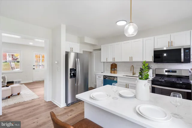 a kitchen with stainless steel appliances kitchen island granite countertop a refrigerator a stove a sink a dining table and chairs with wooden floor