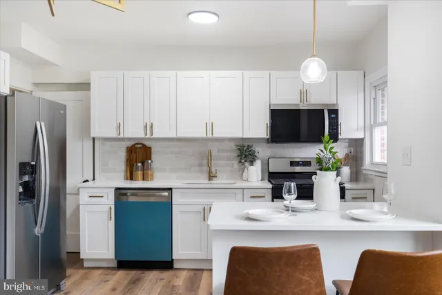 a kitchen with stainless steel appliances a sink a stove a refrigerator cabinets and a dining table