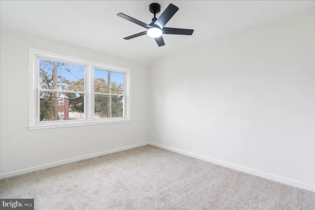 an empty room with a window and a fan
