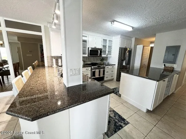 a kitchen with granite countertop stainless steel appliances a sink stove and cabinets
