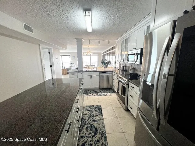 a kitchen with granite countertop a sink and white cabinets