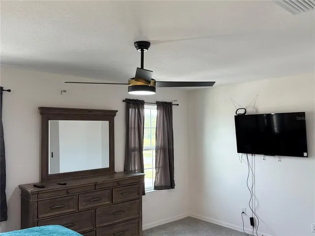 a living room with a flat screen tv and a ceiling fan