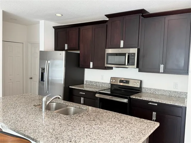 a kitchen with granite countertop a refrigerator stove and microwave