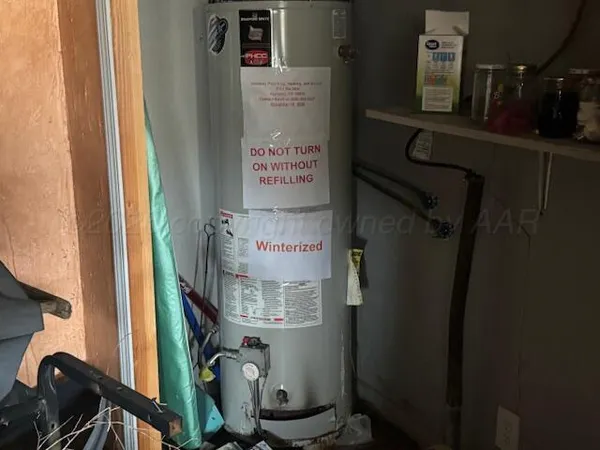 a room with water heater and wooden cabinets