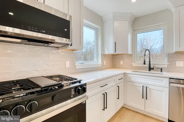 a kitchen with white cabinets and appliances