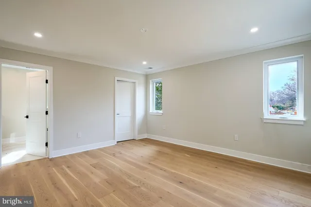 a view of an empty room with wooden floor and window