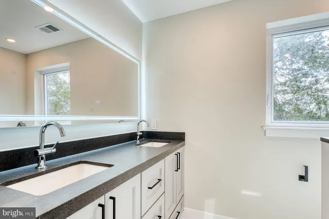 a bathroom with a granite countertop sink and a large mirror