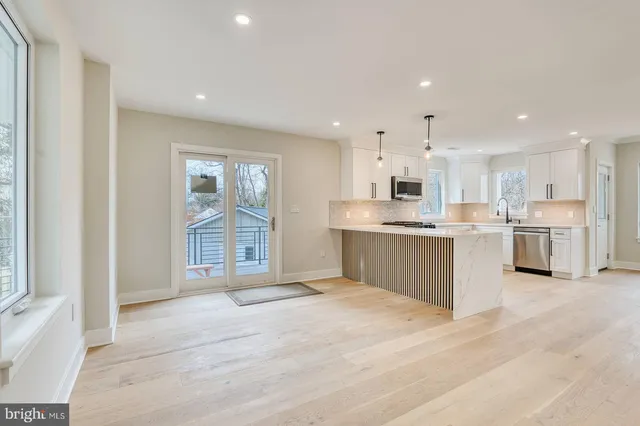 a large white kitchen with kitchen island a sink stainless steel appliances and cabinets