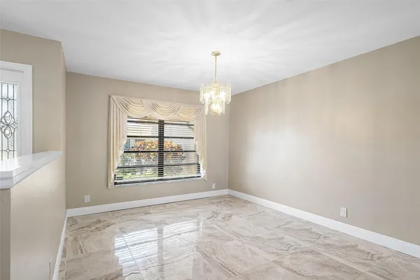 an empty room with windows and chandelier fan