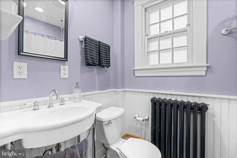 a bathroom with a sink a toilet a mirror and a window