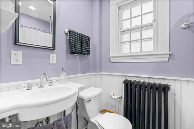 a bathroom with a sink a toilet a mirror and a window