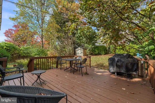 a view of a roof deck with table and chairs a barbeque with wooden floor and fence