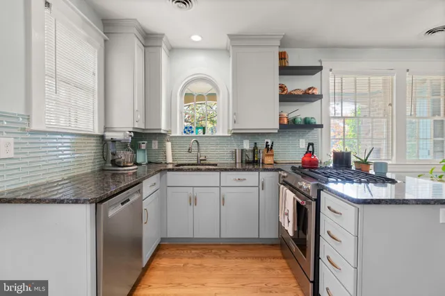 a kitchen with stainless steel appliances granite countertop a sink stove cabinets and a window