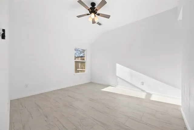 an empty room with windows and fan
