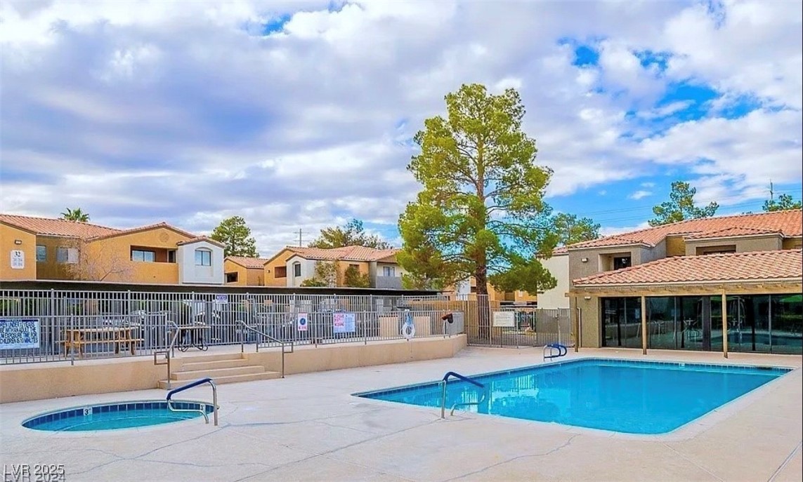 Community pool featuring a patio area, a hot tub, and a residential view