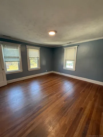a view of an empty room with wooden floor and window