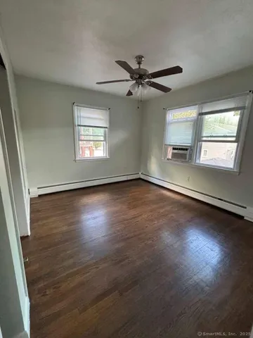 an empty room with wooden floor fan and windows