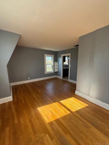 a view of empty room with window and wooden floor