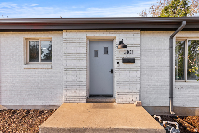 2101 West 3900th Street South Roy, UT 84067 - Photo 4 of 36 White painted brick exterior with a gray front door, featuring a modern black sconce and contemporary house numbers