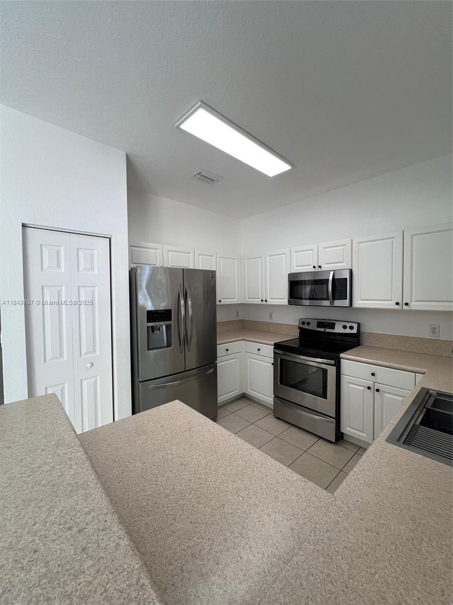 12724 Southwest 133rd Street Miami, FL 33186 - Photo 6 of 33 a kitchen with stainless steel appliances kitchen island a refrigerator sink and stove