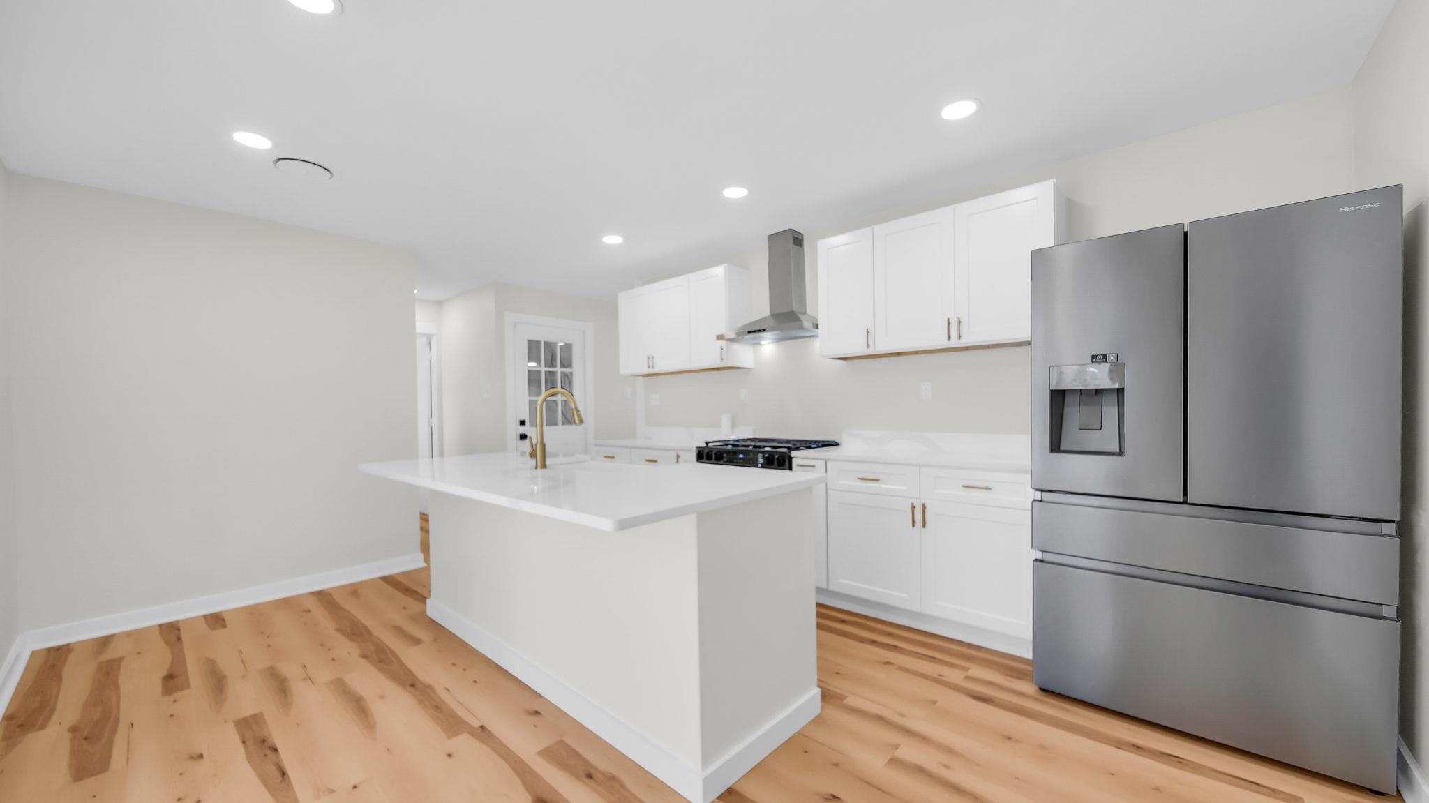 2800 Spring Hill Drive Memphis, TN 38127 - Photo 13 of 31 Kitchen featuring stainless steel fridge, a center island with sink, white cabinets, wall chimney range hood, and recessed lighting