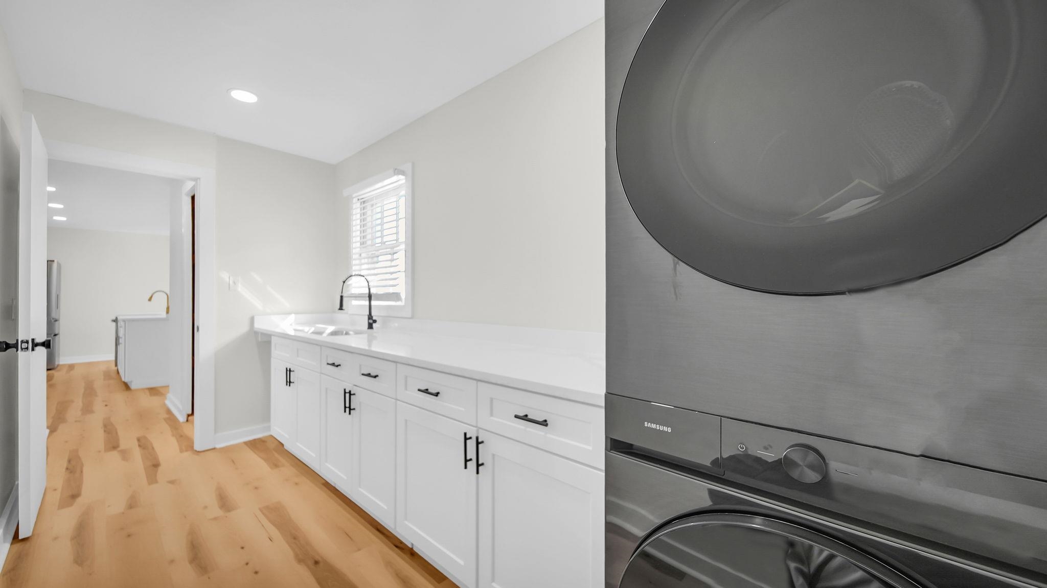 2800 Spring Hill Drive Memphis, TN 38127 - Photo 23 of 31 Laundry room featuring light wood finished floors, recessed lighting, stacked washing machine and dryer, and cabinet space