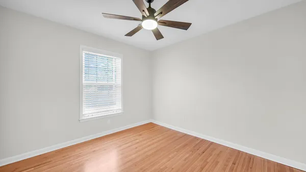 an empty room with a window and a fan