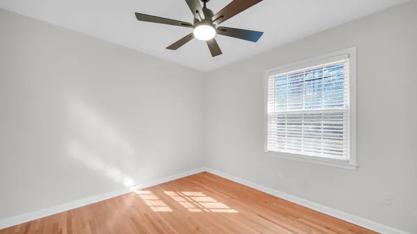 an empty room with a window and a ceiling fan