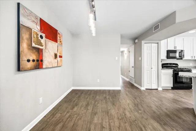 a kitchen with granite countertop a stove and a white kitchen countertops with wooden floor