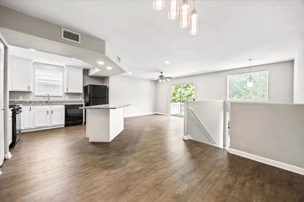an empty room with wooden floor fan and windows