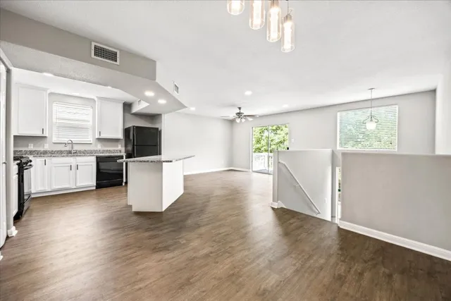 an empty room with wooden floor fan and windows