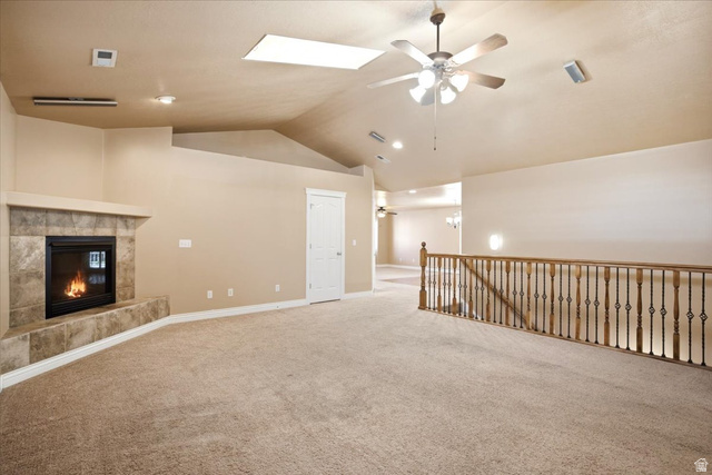 1089 West 2325th Street North Layton, UT 84041 - Photo 15 of 40 Carpeted living area featuring a stone-surround fireplace with hearth, vaulted ceilings, and a skylight