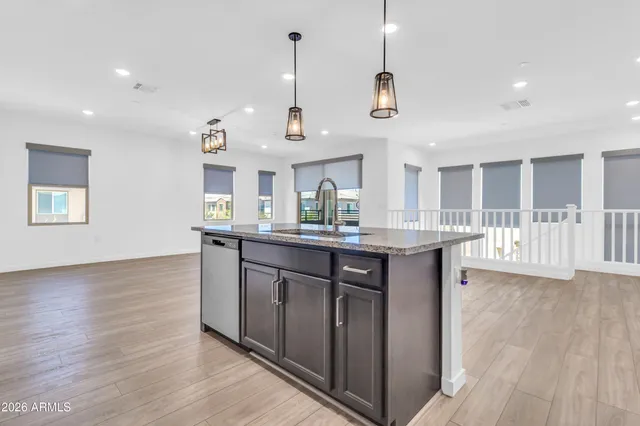 a kitchen with stainless steel appliances granite countertop a sink a stove a refrigerator and white cabinets with wooden floor