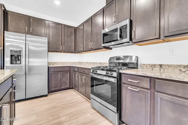 a kitchen with stainless steel appliances granite countertop a sink stove and refrigerator